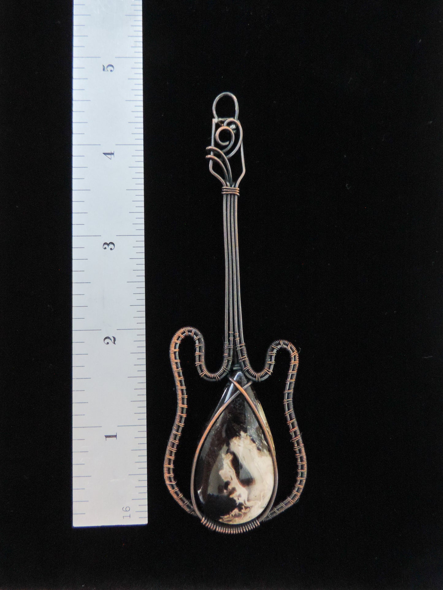 Indonesian Palm Root & Mixed Metals Guitar Pendant. Petrified Palm Root comes from the fossilized root system of Indonesian palm trees. Chalcedony Quartz and Jasper gradually replaced the root wood over millions of years, resulting in a unique material that typically doesn’t have the visible fiber pattern of the tree section but will often have a variety of swirls and colors. Like other fossilized materials,