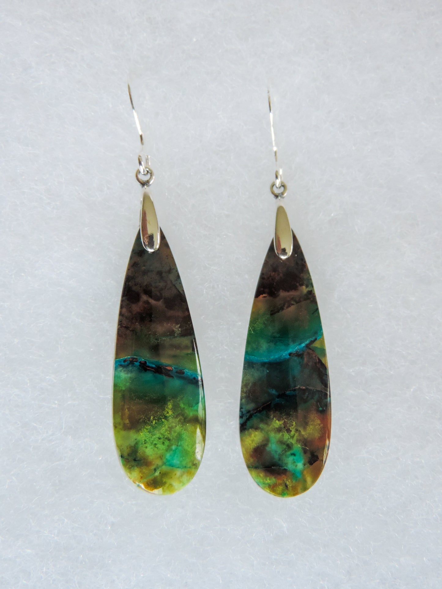 Over thousands of years, the woods’ organic material was replaced with opaline silica rich in copper, iron and manganese minerals.  These rich minerals are responsible for the amazing colors in the stone.  The bail and earring wires are authentic 925 sterling silver.