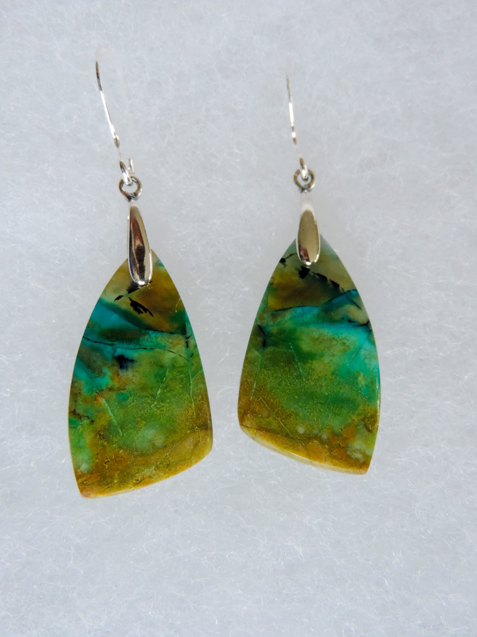 Over thousands of years, the woods’ organic material was replaced with opaline silica rich in copper, iron and manganese minerals.  These rich minerals are responsible for the amazing colors in the stone.  The bail and earring wires are authentic 925 sterling silver.