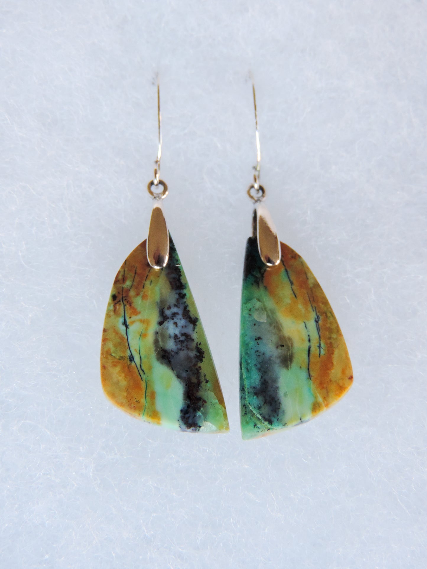 .  Over thousands of years, the woods’ organic material was replaced with opaline silica rich in copper, iron and manganese minerals.  These rich minerals are responsible for the amazing colors in the stone.  The bail and earring wires are authentic 925 sterling silver.