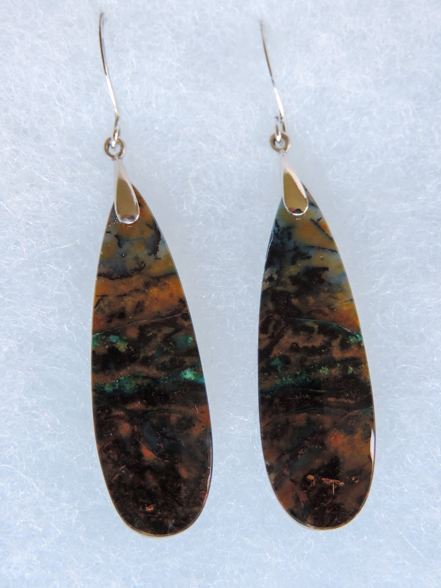 Over thousands of years, the woods’ organic material was replaced with opaline silica rich in copper, iron and manganese minerals. These rich minerals are responsible for the amazing colors in the stone. The bail and earring wires are authentic 925 sterling silver.